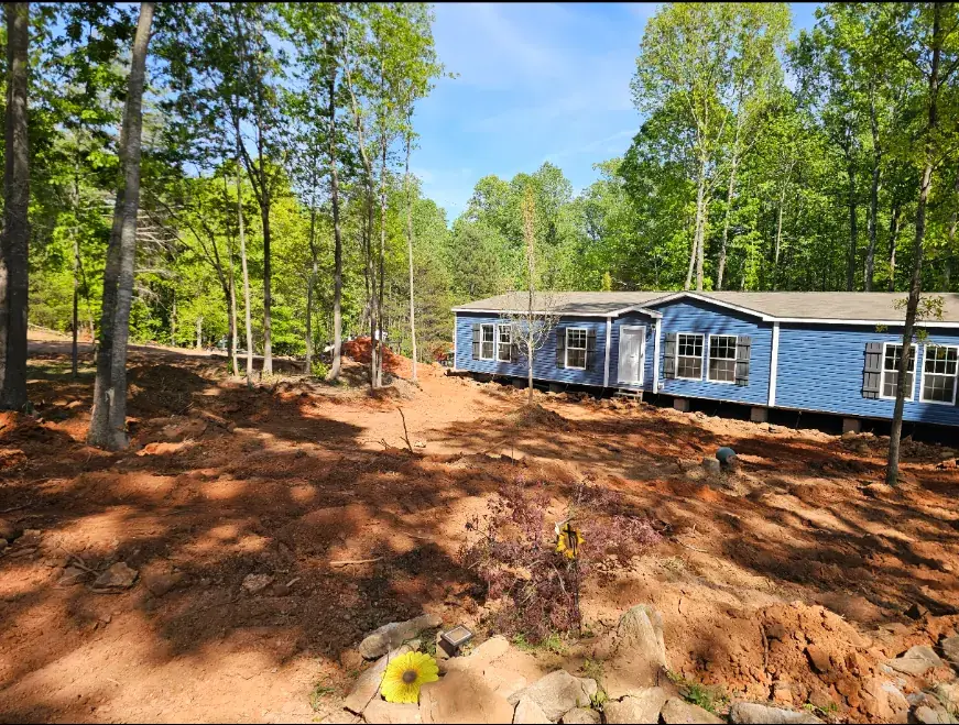 Blue mobile home with the surrounding yard cleared and graded